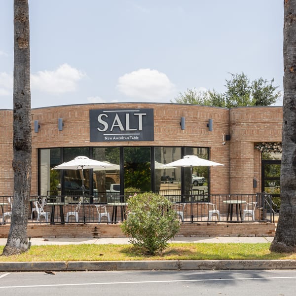 The exterior of SALT New American Table restaurant with outdoor seating and white umbrellas.
