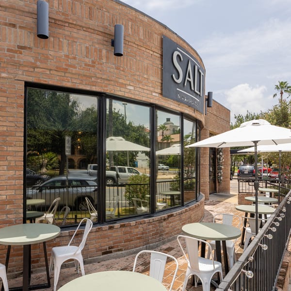 Exterior of SALT New American Table restaurant with outdoor patio seating and white umbrellas.